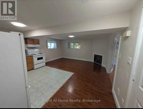 Clarington (Bowmanville) apartment for rent - A spacious room with wood flooring and a white refrigerator.