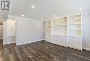 Burlington (Mountainside) apartment for rent - A room with white walls and wooden flooring, featuring built-in shelves and a doorway to another room.