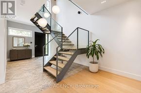 Toronto (North Riverdale) apartment for rent - A modern staircase with glass railings and a potted plant on a wooden floor.