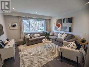 Toronto (Greenwood-Coxwell) triplex for rent - A living room with a grey sofa, a white coffee table, and a rug on the floor.