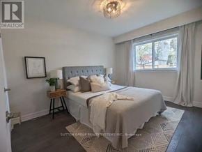 Toronto (Greenwood-Coxwell) triplex for rent - A bedroom with a large bed and a window with curtains.
