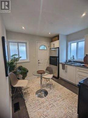 Toronto (Greenwood-Coxwell) triplex for rent - A kitchen with a table and chairs in the middle of the room.