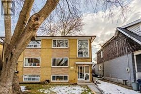 Toronto (Greenwood-Coxwell) triplex for rent - A brick apartment building with a tree in front of it.