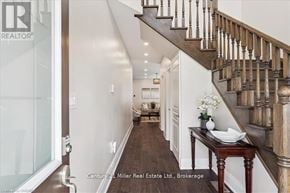 Oakville (Jm Joshua Meadows) apartment for rent - A hallway with a wooden staircase and a table with a vase of flowers on it.