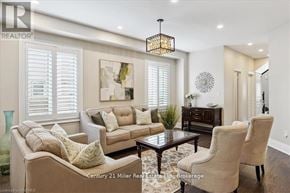 Oakville (Jm Joshua Meadows) apartment for rent - A well-lit living room with a beige sofa, a coffee table, and a chandelier.