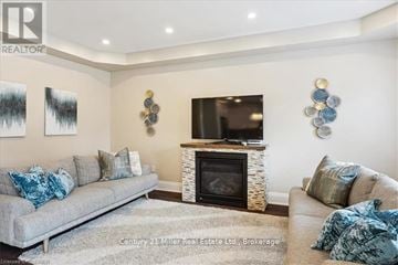 Oakville (Jm Joshua Meadows) apartment for rent - A living room with a grey couch and a fireplace.