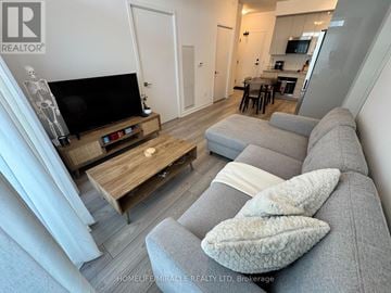 Vaughan (Concord) condo for rent - A living room with a grey couch and a wooden coffee table.