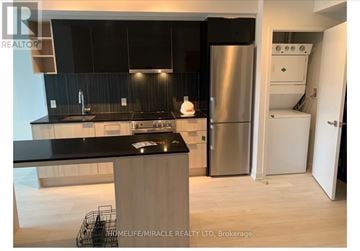 Toronto (Clanton Park) condo for rent - A modern kitchen with a black countertop and stainless steel appliances.