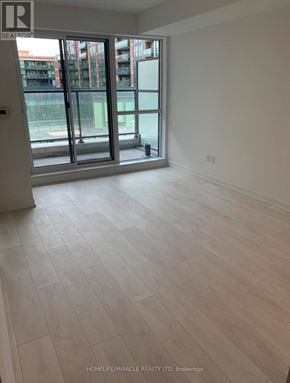 Toronto (Clanton Park) condo for rent - A room with white walls and a wooden floor with a sliding glass door.