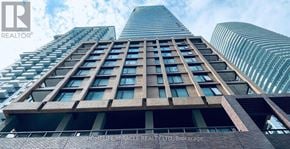 Toronto (Waterfront Communities) condo for rent - A tall building with a glass facade and a sign that reads "HOMELIFE MIRACLE REALTY LTD, Brokerage".