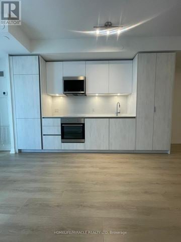 Toronto (Waterfront Communities) condo for rent - A modern kitchen with white cabinets and a wooden floor.