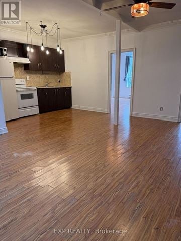 Toronto (Junction Area) multi-family for rent - A room with wooden floors and a kitchen area with a stove and cabinets.