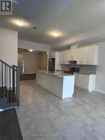 Oakville (Oa Rural Oakville) townhouse for rent - A kitchen with white cabinets and a countertop is shown.