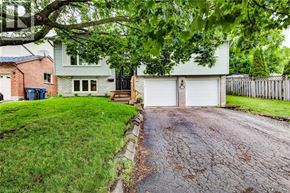 Guelph apartment for rent - A house with a driveway and a tree in front of it.