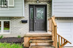Guelph apartment for rent - A house with a black front door and a wooden staircase leading to it.