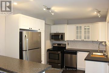 Arnprior townhouse for rent - A kitchen with white cabinets and black appliances.