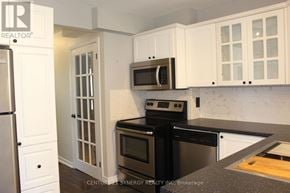 Arnprior townhouse for rent - A kitchen with white cabinets and black appliances.