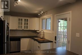 Arnprior townhouse for rent - A kitchen with white cabinets and a black countertop.