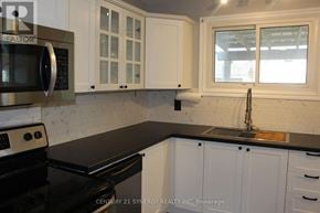 Arnprior townhouse for rent - A kitchen with white cabinets and black countertops.