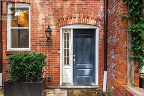 Oakville (Co Central) townhouse for rent - A brick house with a white door and a small bush in front.