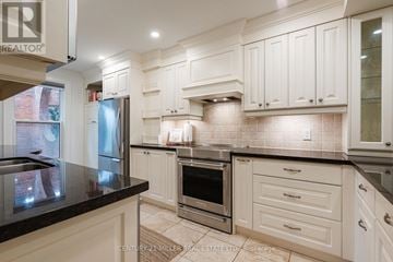 Oakville (Co Central) townhouse for rent - A kitchen with white cabinets and a black countertop.