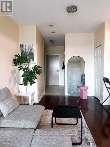 Toronto (Willowdale East) condo for rent - A living room with a grey couch and a black coffee table.