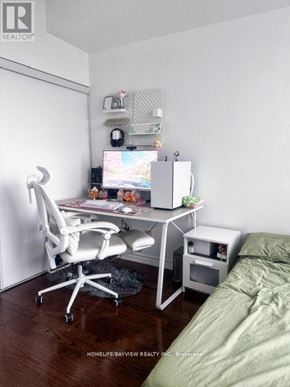 Toronto (Willowdale East) condo for rent - A white computer desk with a chair and a monitor in a room.