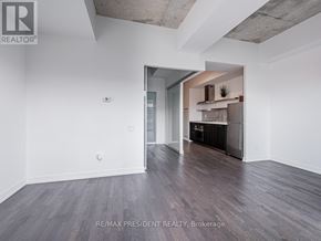 Toronto (Waterfront Communities) condo for rent - A room with a wooden floor and a white wall with a doorway leading to another room.