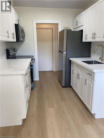 Kitchener apartment for rent - A kitchen with white cabinets and a black fridge.