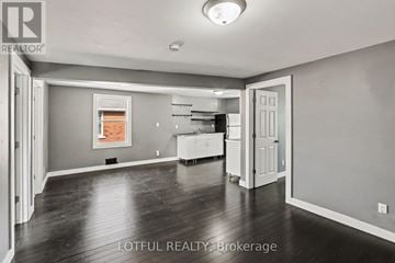 Ottawa triplex for rent - A spacious room with a kitchen area in the background.