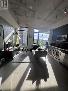 Toronto (Waterfront Communities) condo for rent - A sunny day in a spacious living room with a kitchen area.