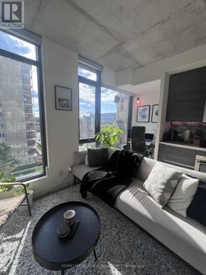 Toronto (Waterfront Communities) condo for rent - A living room with a couch, a table, and a window with a view of a city.