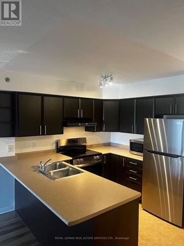 Burlington (Alton) condo for rent - A kitchen with black cabinets and a stainless steel refrigerator.