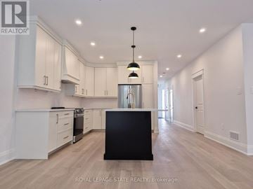 Hamilton (Gourley) apartment for rent - A spacious kitchen with white cabinets and a black island.