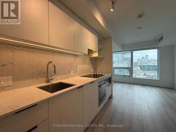 Toronto (Church-Yonge Corridor) condo for rent - A kitchen with white cabinets and a person sitting on the floor.