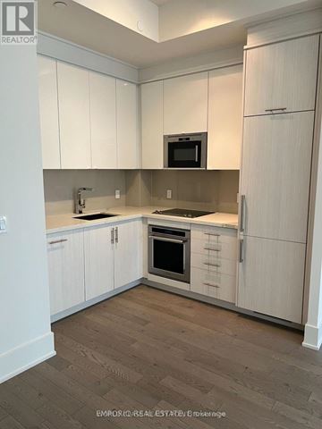 Toronto (Waterfront Communities) condo for rent - A kitchen with white cabinets and a microwave above the stove.