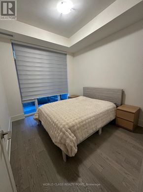 Toronto (Waterfront Communities) condo for rent - A bedroom with a bed, a window with blinds, and a wooden floor.