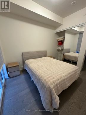 Toronto (Waterfront Communities) condo for rent - A bedroom with a bed, nightstand, and a window.