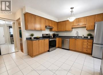 Toronto (Rouge) townhouse for rent - A kitchen with wooden cabinets and a black countertop.