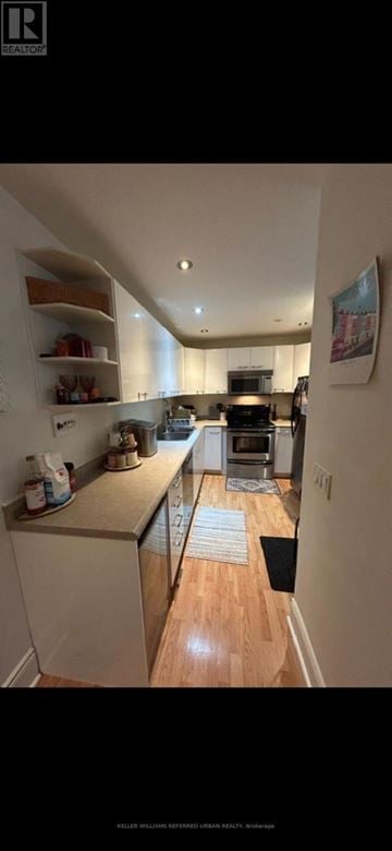 Toronto (University) triplex for rent - A kitchen with a refrigerator, oven, and a rug on the floor.