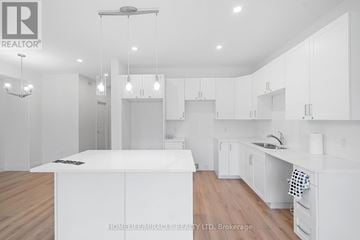 Prince Edward County (Picton) townhouse for rent - A modern kitchen with white cabinets and a wooden floor.