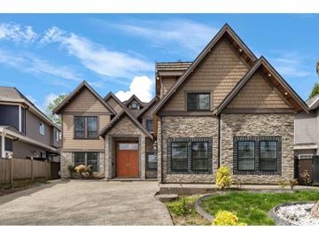 Surrey apartment for rent - A house with a brown roof and a stone wall is surrounded by a fence and has a driveway.