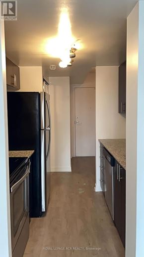 Toronto (Dovercourt-Wallace Emerson-Junction) condo for rent - A kitchen with a black fridge and wooden floors.