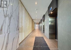 Mississauga (City Centre) condo for rent - A hallway with a marble wall on the left and a carpeted area in the middle.