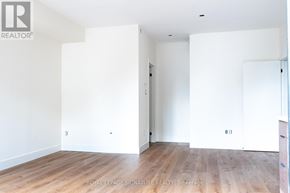 Toronto (Oakwood Village) multi-family for rent - A white room with wooden floors and a door on the right side.