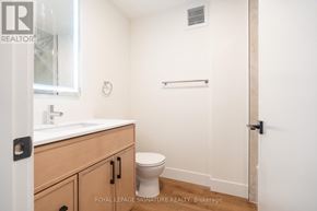 Toronto (Oakwood Village) multi-family for rent - A white bathroom with a toilet, sink, and a towel bar.