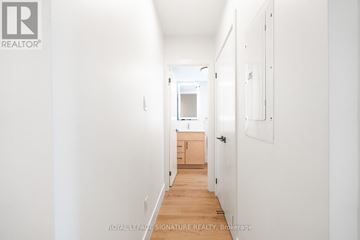 Toronto (Oakwood Village) multi-family for rent - A white hallway with a door on the right and a kitchen visible in the distance.