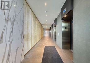 Mississauga (City Centre) condo for rent - A hallway with a marble wall on the left and a glass door on the right.