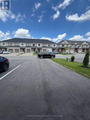 Tillsonburg townhouse for rent - A parking lot in front of a building with cars parked.