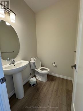 Tillsonburg townhouse for rent - A bathroom with a toilet, sink, and mirror.